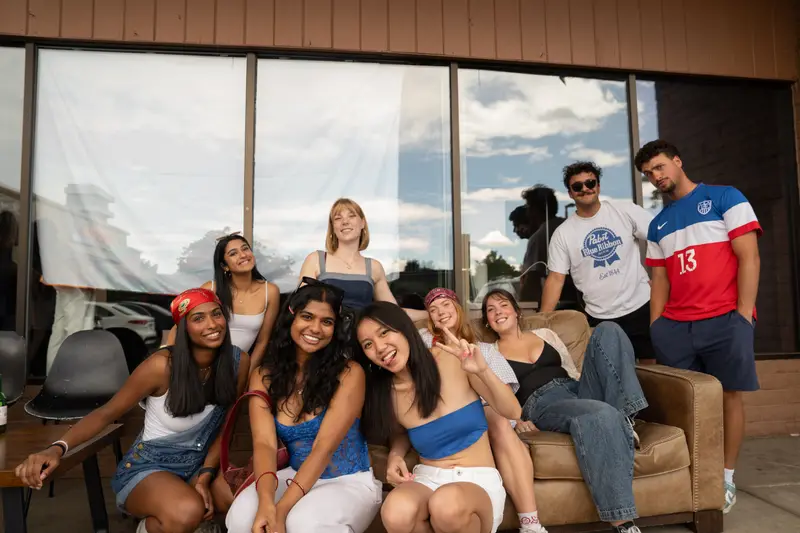A group of friends on a couch outside a venue on a summer afternoon